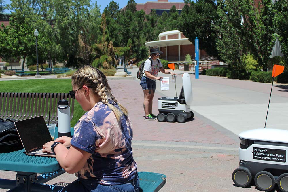 Students outside on the University of Nevada, Reno campus with Starship delivery robots