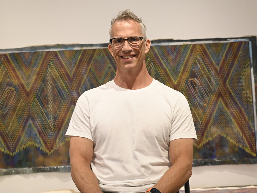 Giordano smiling in front of a tapestry.